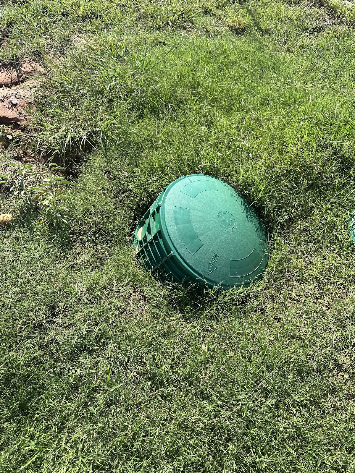 A green septic tank riser lid set into a lawn